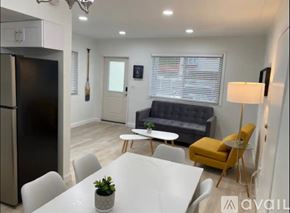 Miami house for rent - A modern kitchen with a black fridge, white dining table, and a grey sofa.