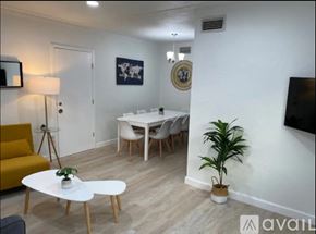 Miami house for rent - A living room with a white table, yellow couch, and a television.