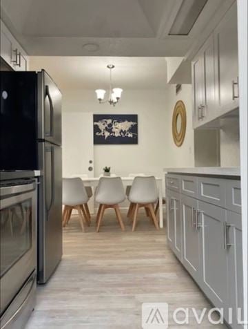 Miami house for rent - A kitchen with a black fridge, wooden chairs and a painting on the wall.