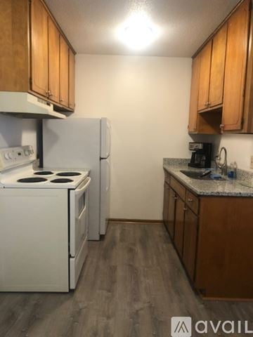 Mankato apartment for rent - A kitchen with a white stove and refrigerator, wooden cabinets, and a granite countertop.