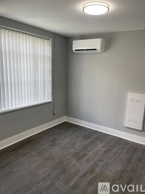 Highland Park apartment for rent - A room with a window covered by white blinds and a wall-mounted air conditioning unit.