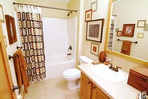 Stilwell house for rent - A bathroom with a white toilet, a white sink, and a shower curtain with a brown pattern.