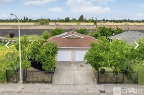 Sacramento house for rent - A house with a garage is surrounded by a black fence and has trees on either side.