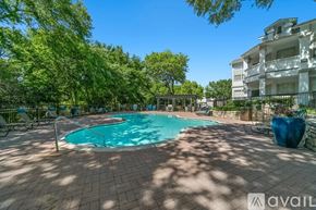 Plano apartment for rent - A pool surrounded by trees and a building in the background.