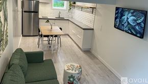 Portland house for rent - A modern kitchen with a dining table and chairs, a refrigerator, and a television mounted on the wall.