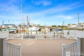Wildwood condo for rent - A wooden deck overlooks a harbor with boats and buildings.