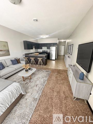 Mankato apartment for rent - A living room with a grey sofa, a white coffee table, and a television on the wall.