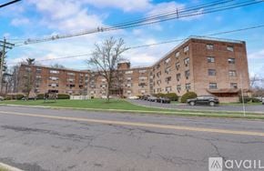 Ewing Township apartment for rent - A large brick apartment building with a parking lot in front.
