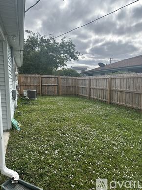 Port St. Lucie house for rent - A backyard with a wooden fence and a grassy area with white flowers.