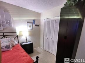 Bradenton condo for rent - A bedroom with a red bed, a black nightstand, and a white wardrobe.