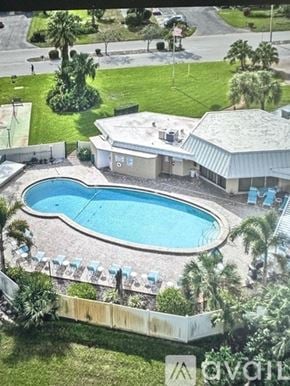 Bradenton condo for rent - A pool surrounded by a white fence and palm trees.