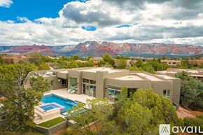Sedona house for rent - A large house with a pool in the foreground and a mountain range in the background.