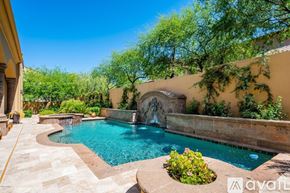 Scottsdale house for rent - A pool with a waterfall and a stone wall.
