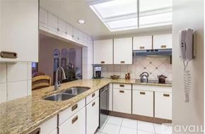 Siesta Key condo for rent - A kitchen with white cabinets and a marble countertop.