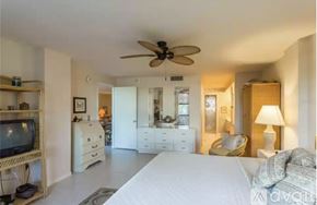 Siesta Key condo for rent - A bedroom with a large bed, a television, and a ceiling fan.