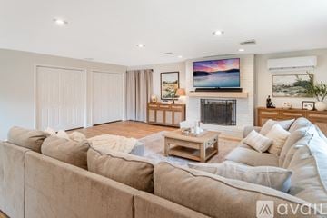 Lafayette house for rent - A living room with a brown leather couch and a wooden dining table.