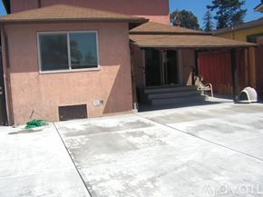 Oakland house for rent - A house with a brown roof and a pink wall with a white window and a white chair outside.