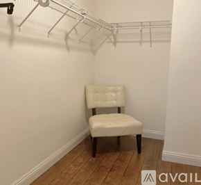 Corona apartment for rent - A white chair with wooden legs sits in a room with a white wall and a clothes rack.