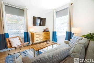 New Castle apartment for rent - A living room with a grey couch, a wooden coffee table, and a chair with a white cushion.