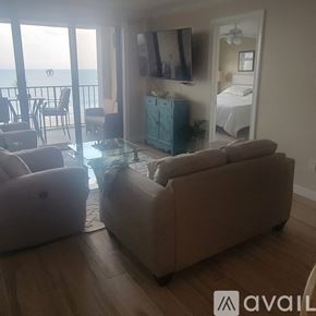Fort Pierce condo for rent - A living room with a couch, chair, and a balcony overlooking the ocean.