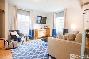 New Castle apartment for rent - A living room with a beige sofa, a chair, and a TV mounted on the wall.