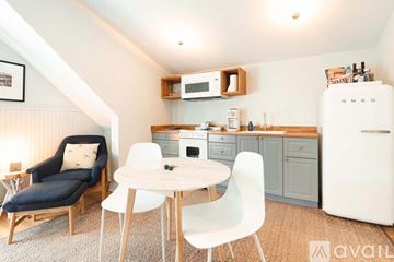 New Castle apartment for rent - A kitchen with a white fridge, a table with chairs and a sofa.