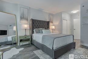 San Diego condo for rent - A bedroom with a large bed, a mirror, and a nightstand with a lamp.
