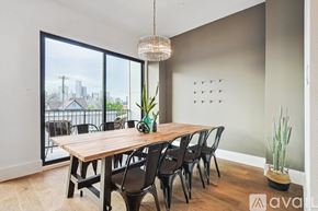Dallas townhouse for rent - A dining room with a wooden table and chairs, a potted plant, and a view of the city through the window.