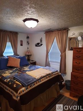 Warrensville house for rent - A bedroom with a bed, dresser, and window with curtains.