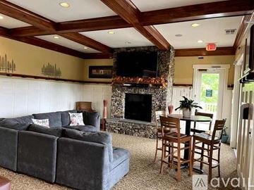 Charlottesville apartment for rent - A living room with a grey couch, a wooden table and chairs, and a stone fireplace.