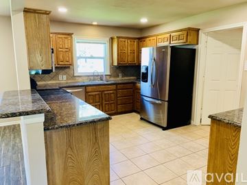 Waxahachie house for rent - A kitchen with wooden cabinets and a black refrigerator.