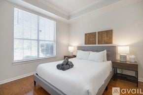 North Richland Hills house for rent - A bedroom with a large bed, a window with blinds, and a nightstand with a lamp.