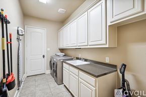 Rowlett house for rent - A kitchen with white cabinets and a washing machine.