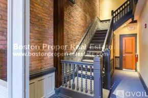 Boston apartment for rent - A staircase with a black railing leads to a door in a building.