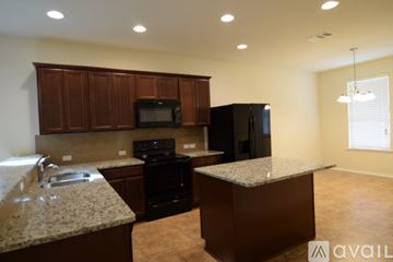Killeen house for rent - A kitchen area with a black refrigerator and brown cabinets.