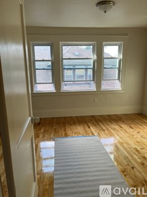 Boston apartment for rent - A room with wooden floors and a window overlooking a building.