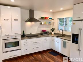 Manzanita house for rent - A modern kitchen with white cabinets and wooden floors.