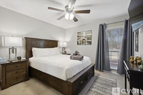 Garland house for rent - A bedroom with a large bed, a ceiling fan, and a nightstand with a lamp.