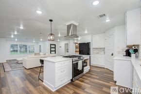 Houston house for rent - A modern kitchen with white cabinets and a wooden floor.