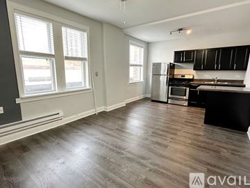 Chicago apartment for rent - A kitchen with black cabinets and a wooden floor.
