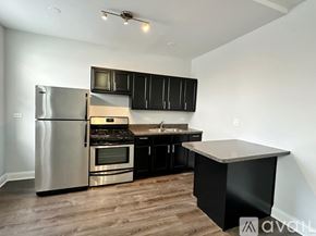 Chicago apartment for rent - A kitchen with a stainless steel refrigerator, black cabinets, and a wooden island.