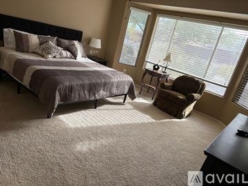 Surprise apartment for rent - A bedroom with a large bed and a chair by the window.