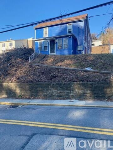 Morgantown apartment for rent - A blue house with a white door and windows is situated on a hill.