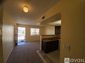 Bullhead City apartment for rent - A room with a carpet floor and a kitchen area with brown cabinets.