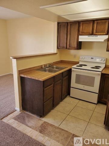 Bullhead City apartment for rent - A kitchen with a white stove and wooden cabinets.