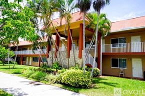 Deerfield Beach apartment for rent - A building with a red roof and a balcony is surrounded by greenery.