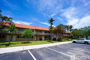 Deerfield Beach apartment for rent - A car is parked in a parking lot in front of a building with a red roof.