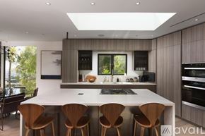 West Hollywood house for rent - A modern kitchen with a large island and wooden chairs.