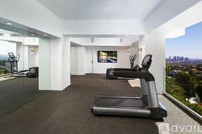 West Hollywood house for rent - A spacious room with a treadmill and a television.