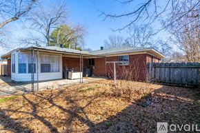 Jacksonville house for rent - A house with a red brick exterior and a white window is surrounded by a fence and trees.